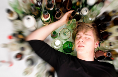 Intoxicated teen lying on the floor next to bottles