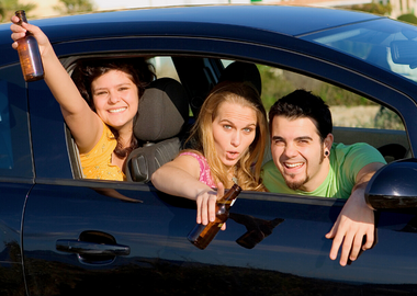 Teen holding bottles of beer while riding a car